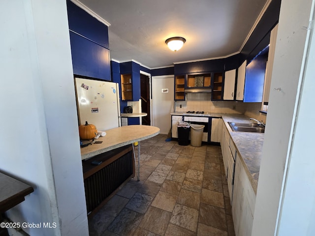 kitchen featuring sink, backsplash, white fridge, crown molding, and blue cabinetry