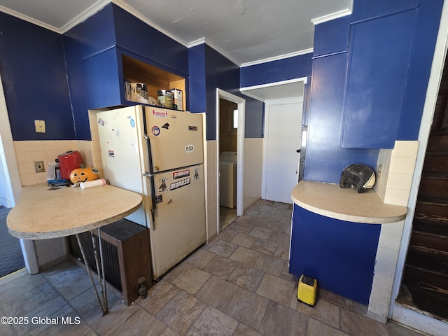 kitchen featuring tile walls, washer / dryer, blue cabinetry, and white refrigerator