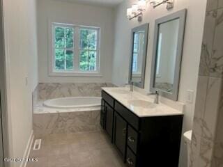 bathroom with vanity and tiled bath