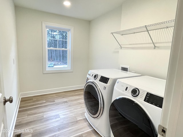 laundry area featuring washer and dryer and light hardwood / wood-style flooring