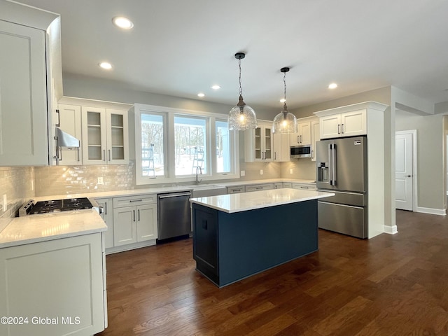 kitchen featuring dark wood-type flooring, white cabinetry, a center island, appliances with stainless steel finishes, and pendant lighting