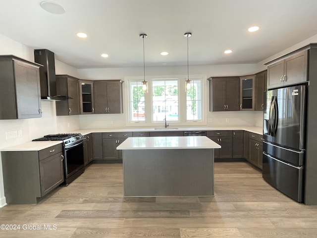 kitchen featuring a kitchen island, sink, wall chimney exhaust hood, stainless steel appliances, and light hardwood / wood-style flooring