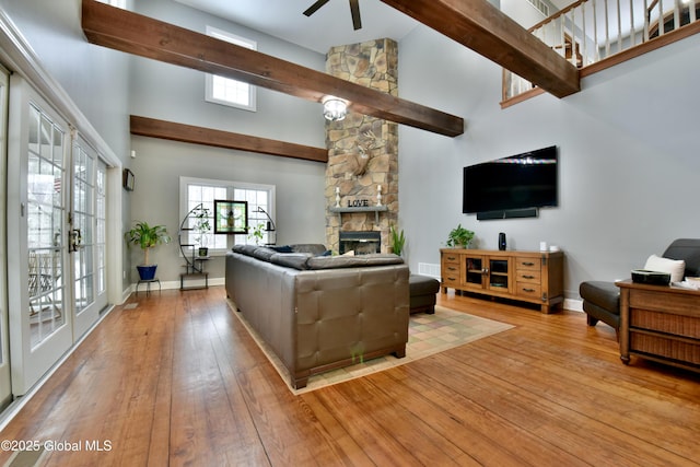 living room featuring a healthy amount of sunlight, a fireplace, light wood-style flooring, and a high ceiling