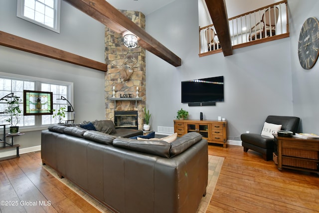 living area with light wood-style flooring, a towering ceiling, and baseboards