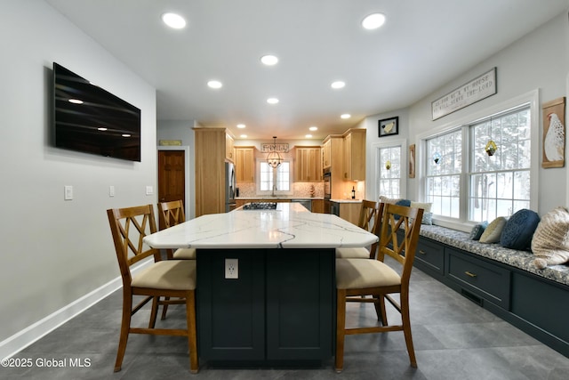 kitchen featuring tasteful backsplash, stainless steel fridge with ice dispenser, a center island, gas stovetop, and a kitchen bar