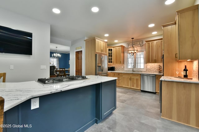 kitchen with a notable chandelier, stainless steel appliances, a sink, tasteful backsplash, and pendant lighting