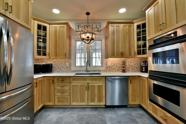 kitchen featuring stainless steel appliances, a sink, light countertops, tasteful backsplash, and decorative light fixtures