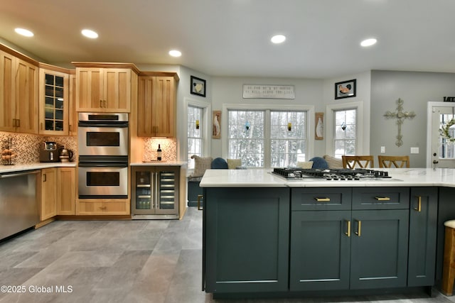 kitchen with stainless steel appliances, light countertops, decorative backsplash, green cabinets, and beverage cooler