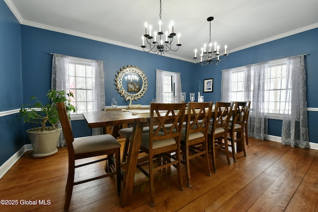 dining room with hardwood / wood-style floors, crown molding, a wealth of natural light, and a notable chandelier