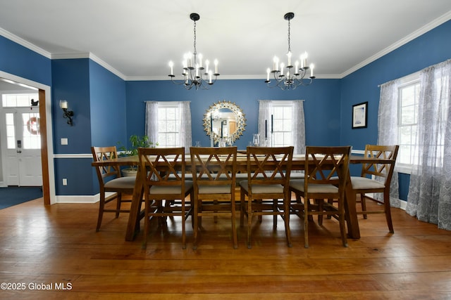 dining space with a wealth of natural light, crown molding, hardwood / wood-style floors, and an inviting chandelier