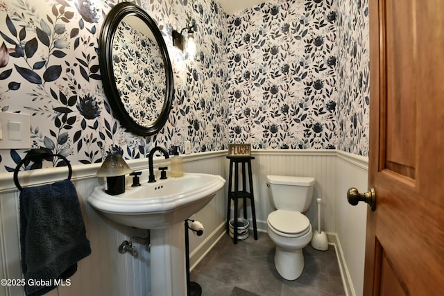 bathroom with toilet, a wainscoted wall, wallpapered walls, and tile patterned floors