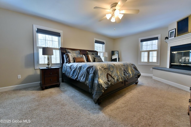 carpeted bedroom with ceiling fan, baseboards, and a tile fireplace