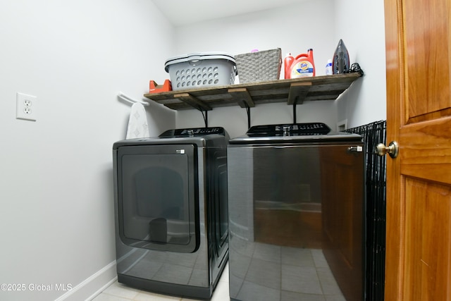 clothes washing area featuring laundry area, light tile patterned floors, baseboards, and washer and clothes dryer