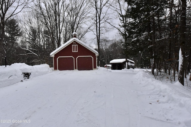 yard layered in snow with a detached garage and an outbuilding