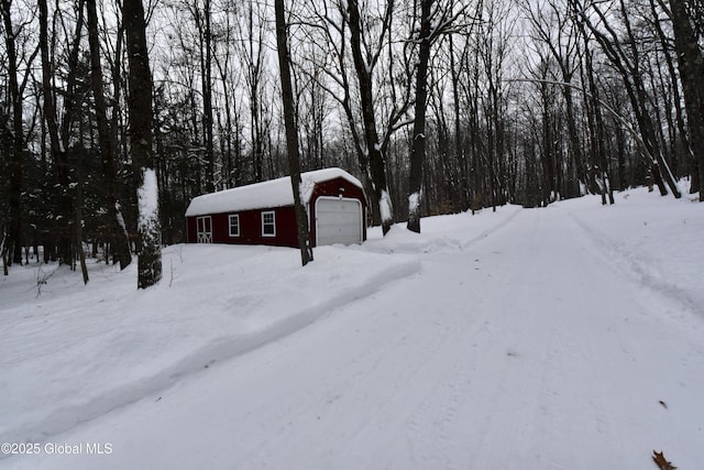 yard covered in snow featuring a garage and an outbuilding