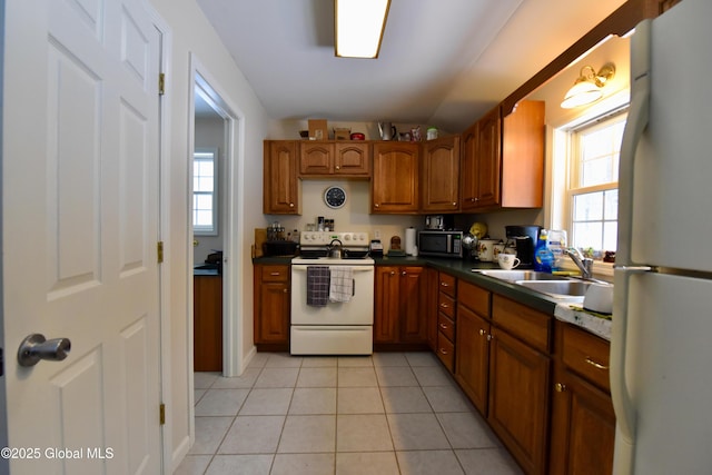 kitchen with light tile patterned floors, white appliances, a sink, and brown cabinets