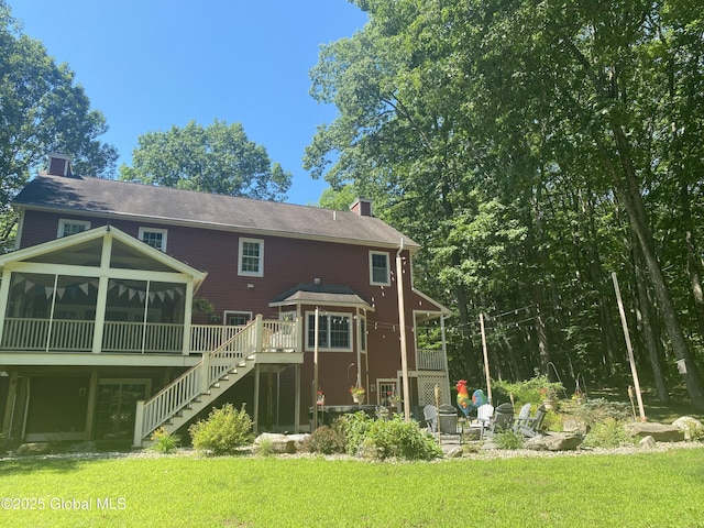 back of property with a sunroom, a lawn, a chimney, and stairs