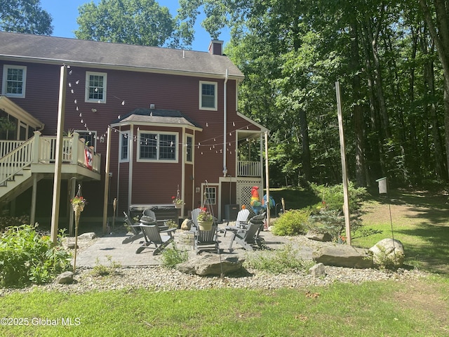 rear view of house featuring a deck, a chimney, a patio area, and stairway