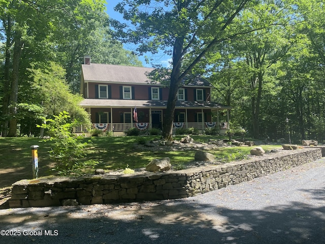 colonial house featuring a chimney and a porch