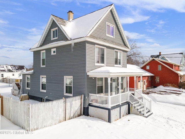 snow covered rear of property featuring covered porch