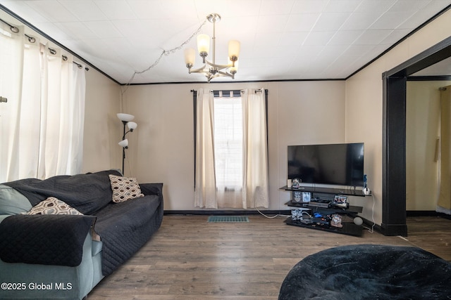 living room featuring hardwood / wood-style flooring, ornamental molding, and a chandelier