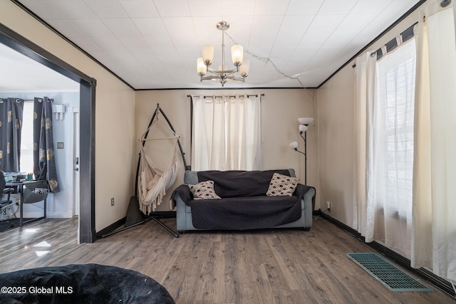 living area featuring crown molding, wood-type flooring, and a chandelier