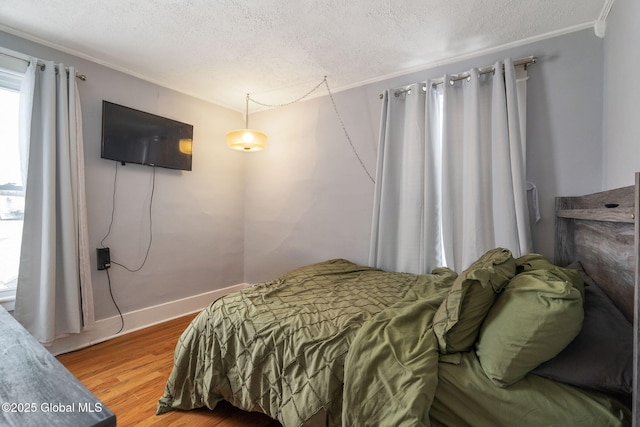 bedroom with wood-type flooring, crown molding, and a textured ceiling