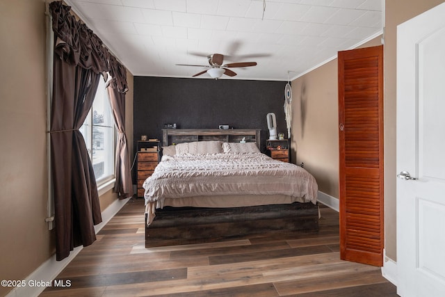 bedroom featuring crown molding, dark wood-type flooring, and ceiling fan