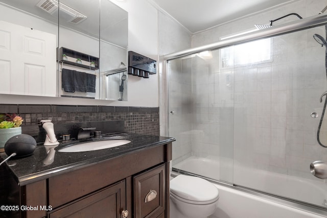 full bathroom featuring bath / shower combo with glass door, vanity, backsplash, and toilet