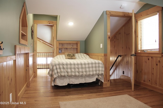 bedroom featuring vaulted ceiling, wooden walls, and wood-type flooring