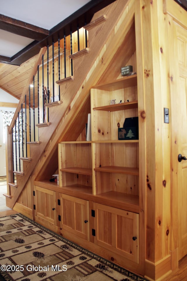 stairs featuring vaulted ceiling and wood walls