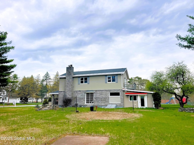 rear view of property with a chimney, a yard, stone siding, and stucco siding