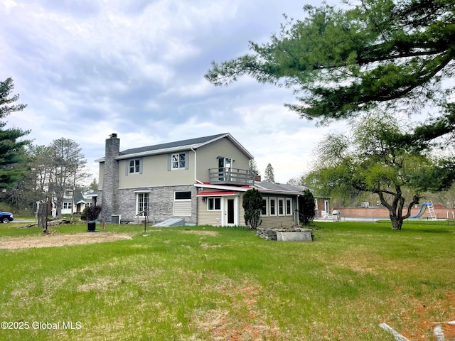 back of property featuring central air condition unit, stone siding, a chimney, a yard, and stucco siding