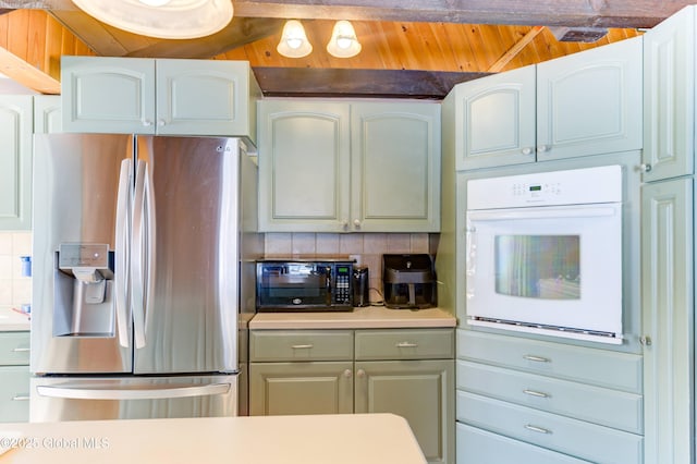 kitchen with stainless steel refrigerator with ice dispenser, oven, decorative backsplash, and white cabinets