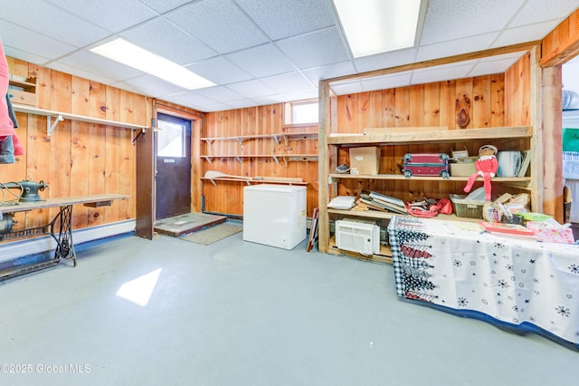 interior space featuring a drop ceiling, concrete floors, and wood walls