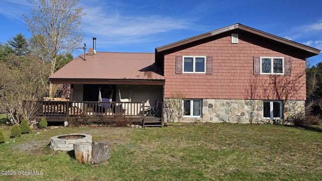 back of property with a yard and a fire pit