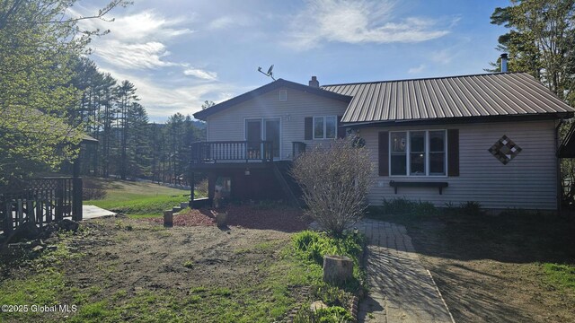 back of property with a wooden deck, a chimney, stairs, and metal roof