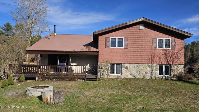 rear view of house with a yard and an outdoor fire pit