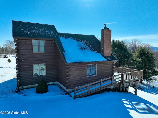 snow covered back of property featuring a deck