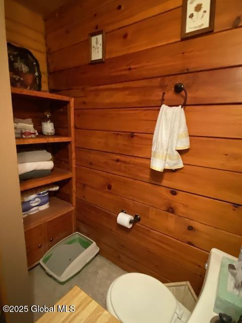 bathroom featuring wooden walls and toilet