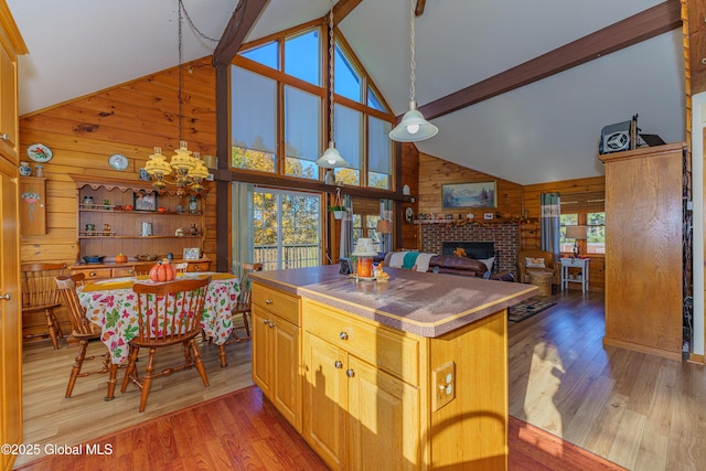 kitchen featuring decorative light fixtures, light hardwood / wood-style floors, a brick fireplace, and wood walls