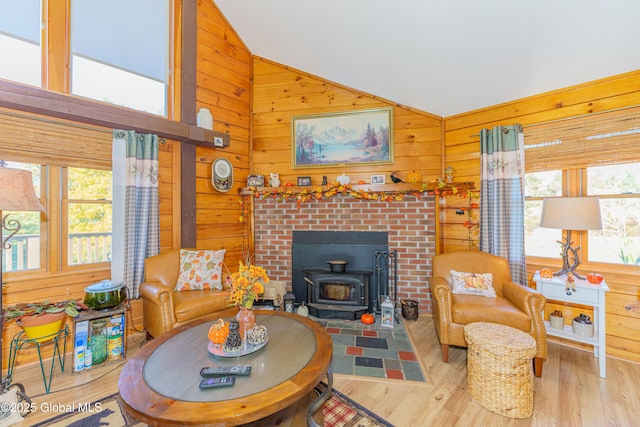 living room featuring vaulted ceiling, light hardwood / wood-style flooring, a wealth of natural light, and wood walls