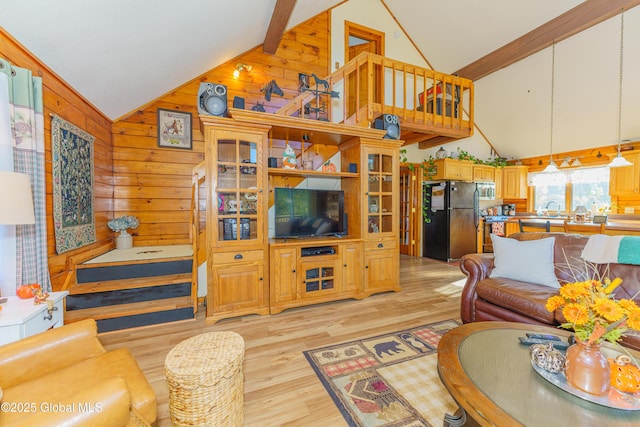 living room featuring high vaulted ceiling, wood walls, sink, beam ceiling, and light hardwood / wood-style flooring