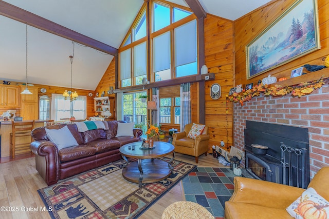 living room with high vaulted ceiling, hardwood / wood-style floors, an inviting chandelier, and wood walls