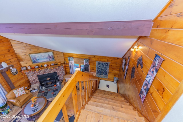 staircase with vaulted ceiling with beams, wood-type flooring, a wood stove, and wood walls