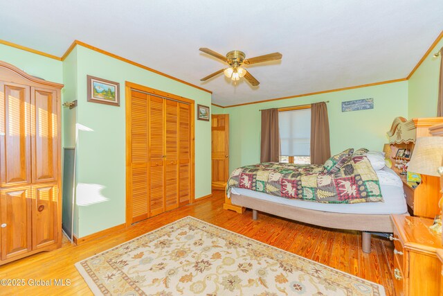 bedroom featuring hardwood / wood-style flooring, ornamental molding, ceiling fan, and a closet