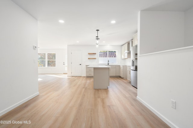 kitchen featuring pendant lighting, sink, stainless steel refrigerator with ice dispenser, light hardwood / wood-style floors, and a kitchen island