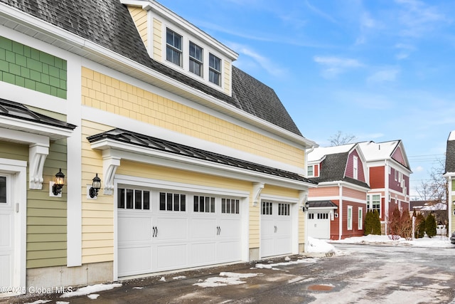 view of front of house with a standing seam roof, metal roof, roof with shingles, and an attached garage