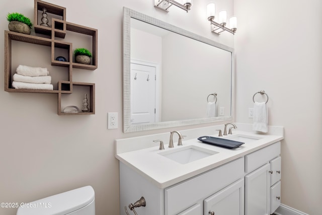 bathroom with double vanity, toilet, and a sink