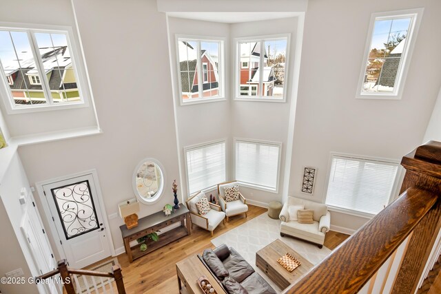 living area with light wood-style flooring, a high ceiling, baseboards, and stairs